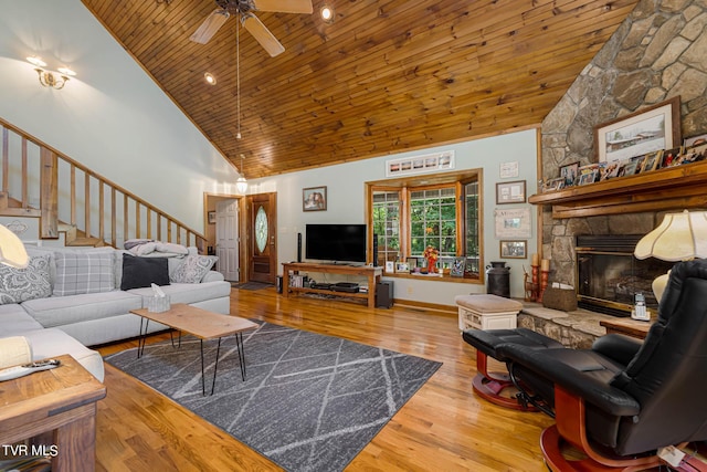 living room featuring high vaulted ceiling, a stone fireplace, wooden ceiling, wood finished floors, and stairway