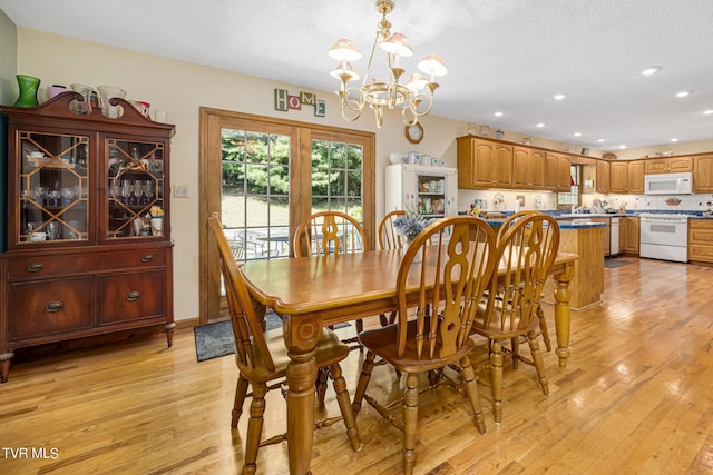 dining room featuring light wood-style floors, a textured ceiling, a notable chandelier, and recessed lighting