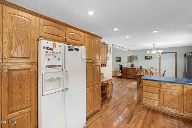 kitchen featuring brown cabinets, decorative light fixtures, light wood-style floors, white fridge with ice dispenser, and a chandelier