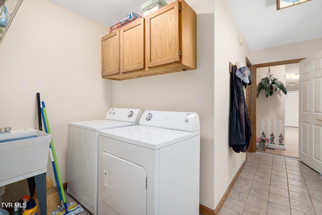 laundry room featuring cabinet space, light tile patterned floors, baseboards, washer and clothes dryer, and a sink