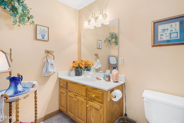 half bathroom with toilet, tile patterned flooring, baseboards, and vanity