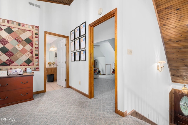 hallway featuring carpet floors, wood ceiling, visible vents, and baseboards