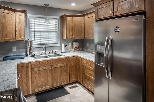 kitchen with stainless steel fridge with ice dispenser, light countertops, pendant lighting, a sink, and light tile patterned flooring