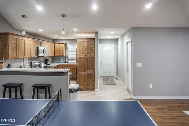 kitchen with pendant lighting, stainless steel appliances, recessed lighting, brown cabinetry, and a peninsula