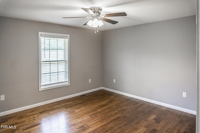 spare room featuring a ceiling fan, dark wood finished floors, visible vents, and baseboards