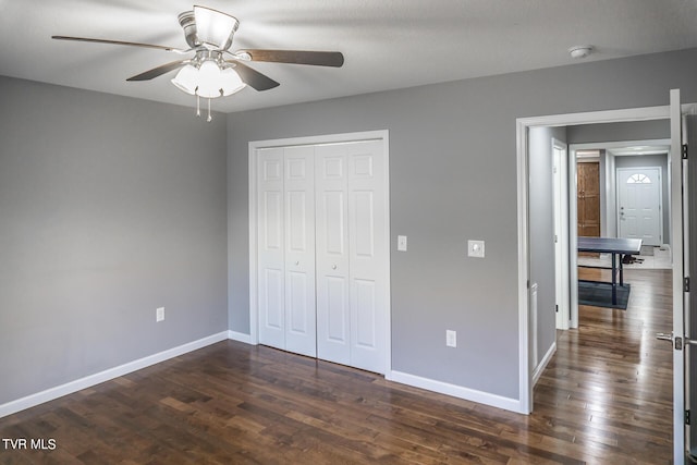 unfurnished bedroom with dark wood-style floors, ceiling fan, a closet, and baseboards