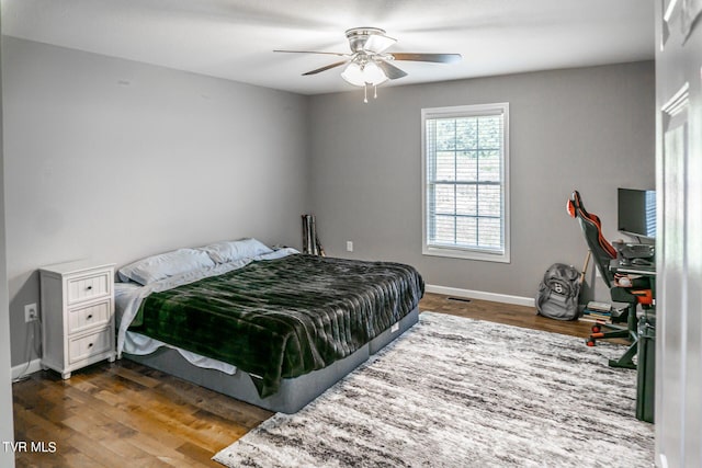 bedroom featuring visible vents, ceiling fan, baseboards, and wood finished floors