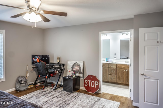 bedroom featuring light wood-type flooring, ensuite bath, a ceiling fan, and baseboards