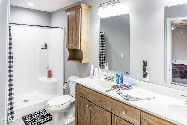 bathroom featuring toilet, a stall shower, double vanity, and a sink