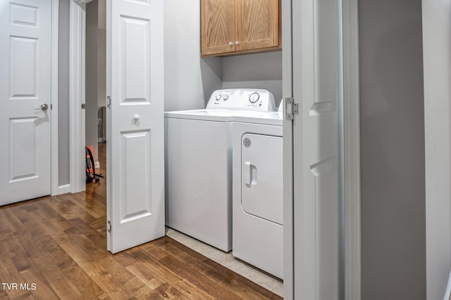 washroom with dark hardwood / wood-style floors, separate washer and dryer, and cabinets