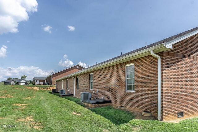 view of property exterior with cooling unit, crawl space, brick siding, and a yard