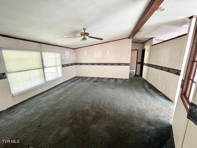 unfurnished room featuring ceiling fan, beamed ceiling, and dark carpet