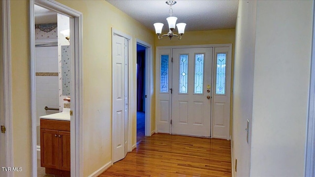 foyer featuring a textured ceiling, a notable chandelier, and light hardwood / wood-style flooring