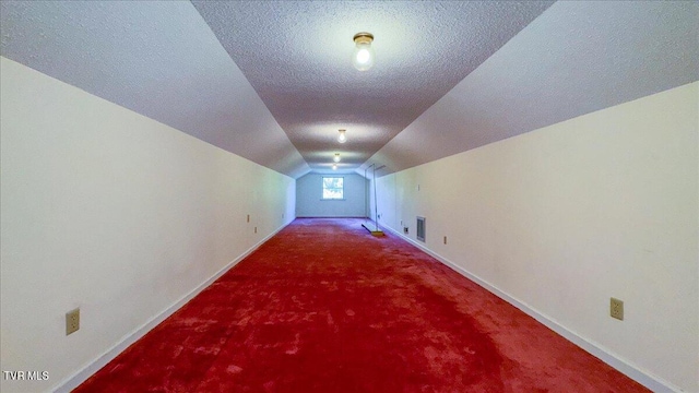 bonus room featuring a textured ceiling, vaulted ceiling, and carpet floors