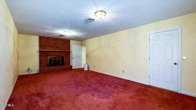 unfurnished living room with a fireplace, carpet, a textured ceiling, and brick wall