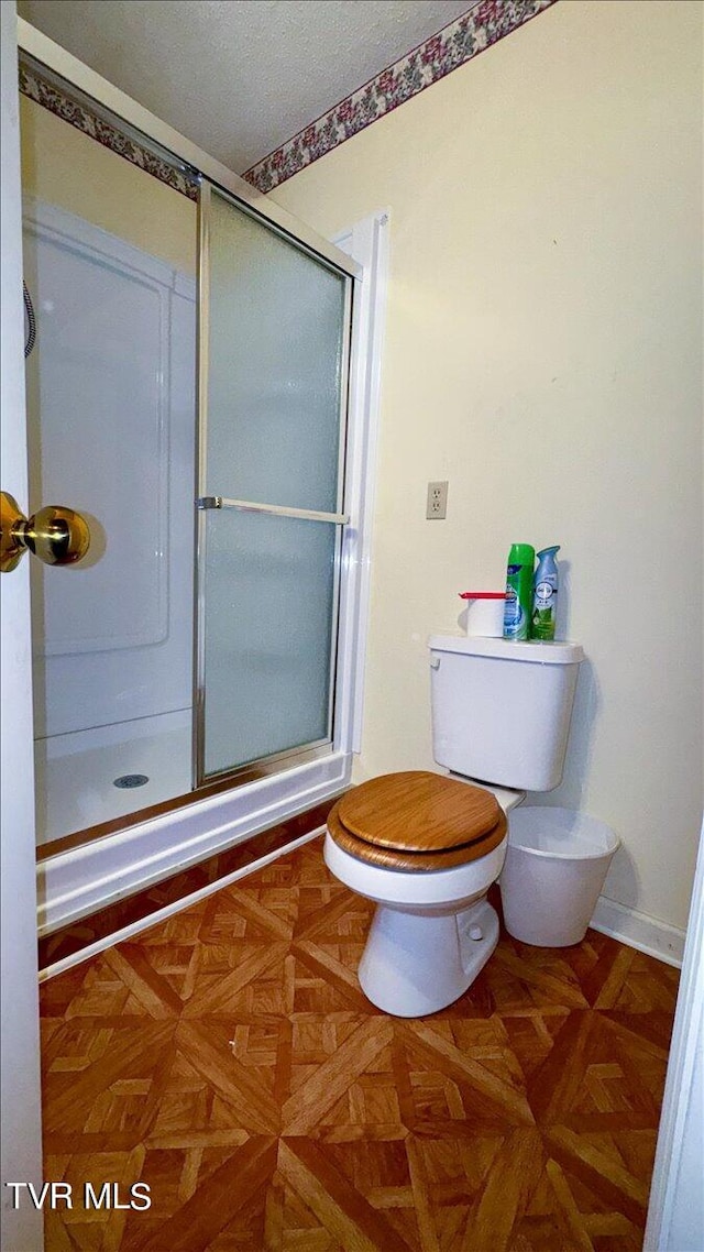 bathroom with an enclosed shower, parquet floors, and toilet