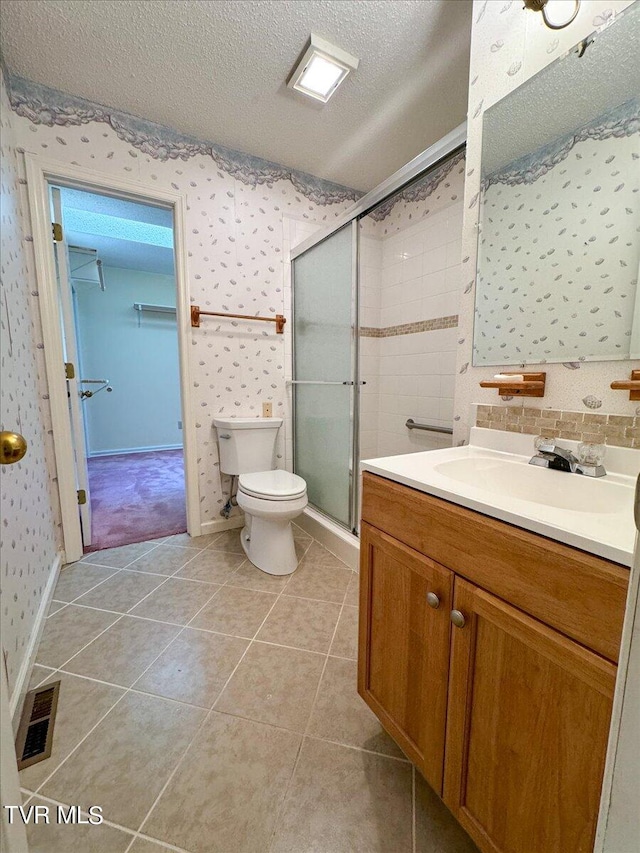 bathroom with tile patterned flooring, an enclosed shower, toilet, vanity, and a textured ceiling