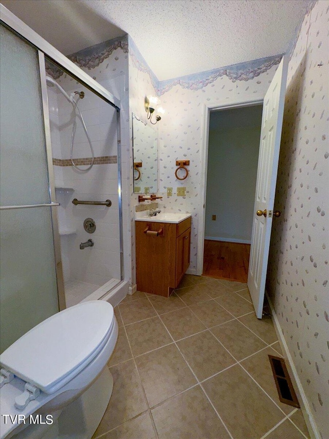 bathroom featuring vanity, a shower with shower door, tile patterned floors, and toilet