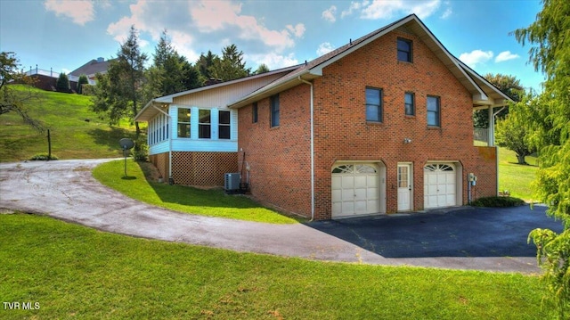 view of side of property with a yard, a garage, and central AC unit