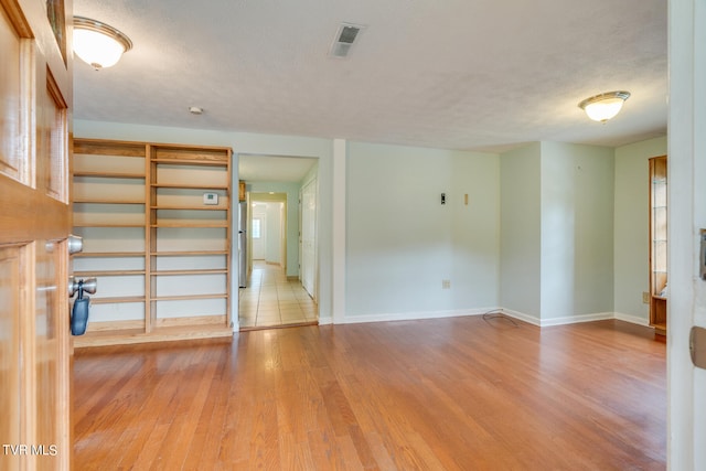 empty room featuring light wood-type flooring and a textured ceiling