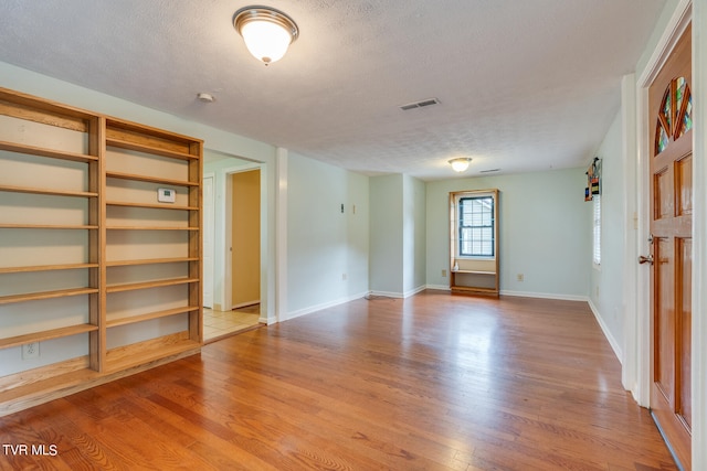 empty room featuring a textured ceiling and light hardwood / wood-style floors