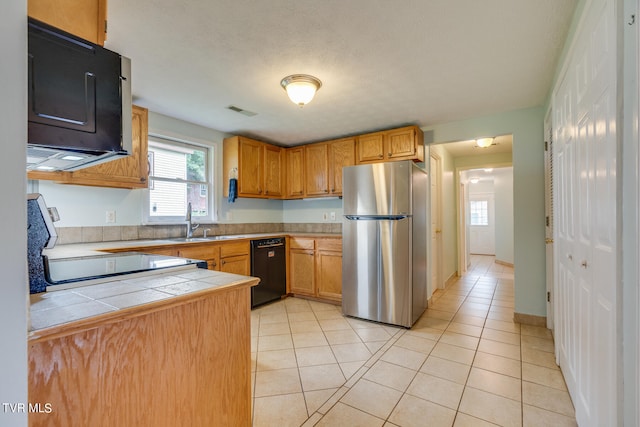 kitchen with sink, light tile patterned flooring, black appliances, and tile counters