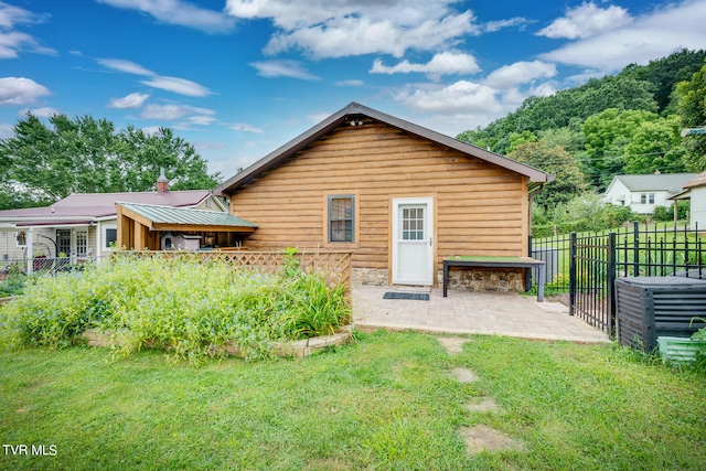 back of house with a patio and a lawn