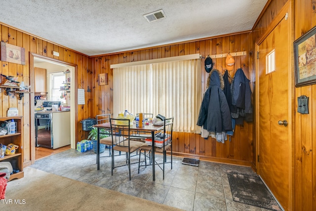 dining space with wood walls, ornamental molding, a textured ceiling, and tile patterned floors