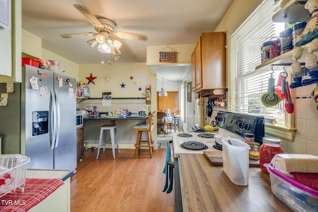 kitchen with stainless steel appliances, ceiling fan, and light hardwood / wood-style floors