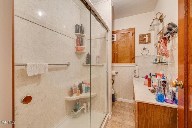 bathroom featuring tile walls, tile patterned flooring, an enclosed shower, and vanity