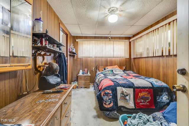 bedroom featuring a paneled ceiling, ceiling fan, and wooden walls