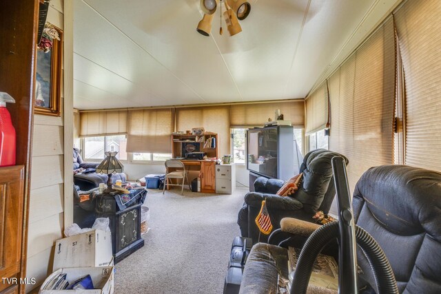 carpeted living room featuring wood walls and ceiling fan