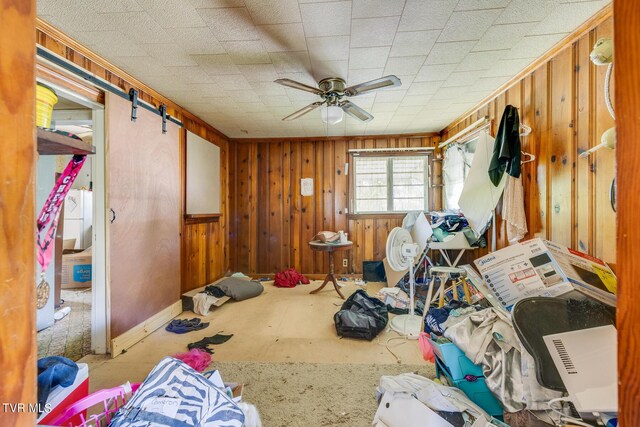 misc room featuring ceiling fan and wooden walls