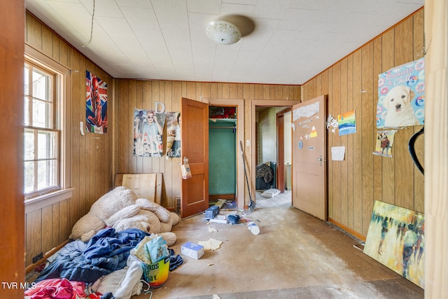 misc room with plenty of natural light, concrete flooring, and wooden walls