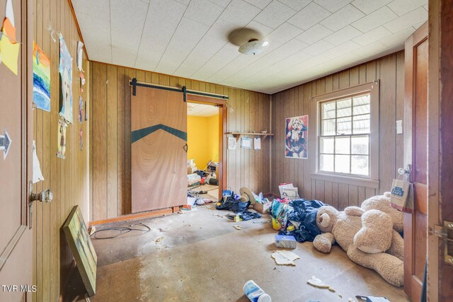 misc room featuring a barn door and wood walls