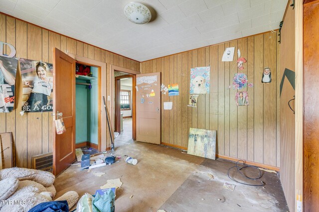 misc room with concrete flooring and wooden walls