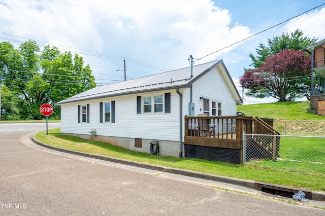 view of side of property with a wooden deck and a lawn