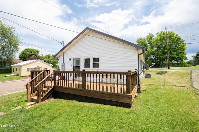 rear view of house featuring a storage shed, a lawn, and a deck