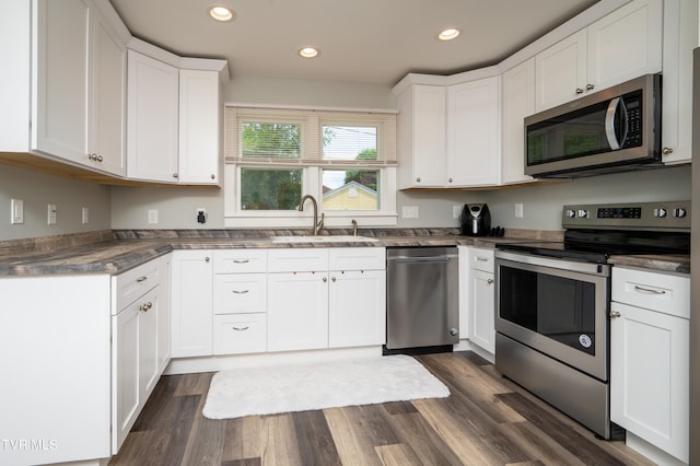 kitchen with dark wood-type flooring, stainless steel appliances, white cabinetry, and sink