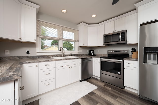 kitchen featuring stainless steel appliances, sink, dark hardwood / wood-style flooring, and white cabinets