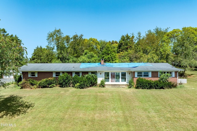 ranch-style house with brick siding, a chimney, and a front yard