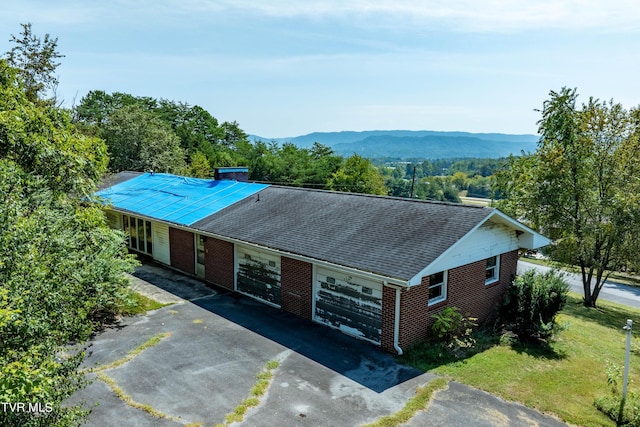 view of front of property featuring aphalt driveway, brick siding, a mountain view, and an attached garage