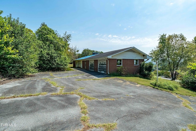 view of front facade with a garage, driveway, and brick siding