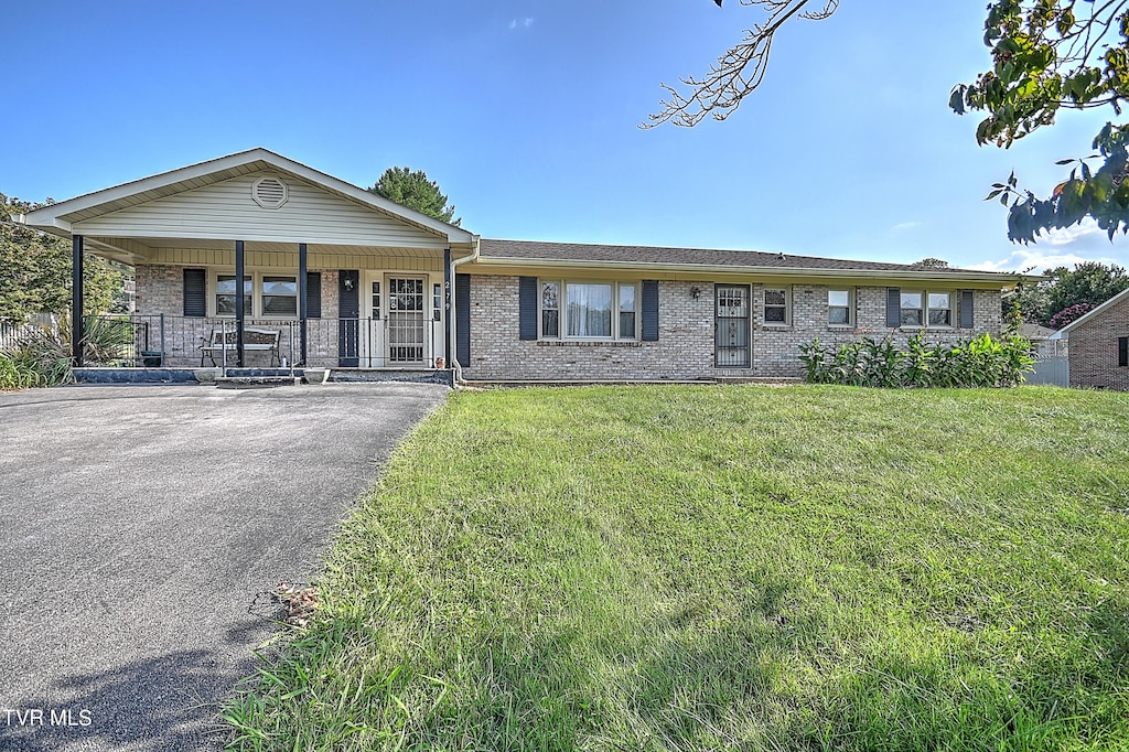 ranch-style house with a porch and a front lawn