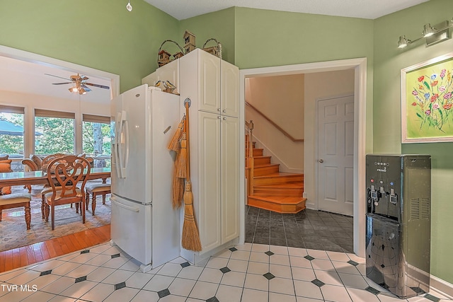 kitchen with light tile patterned floors, white cabinets, freestanding refrigerator, and ceiling fan