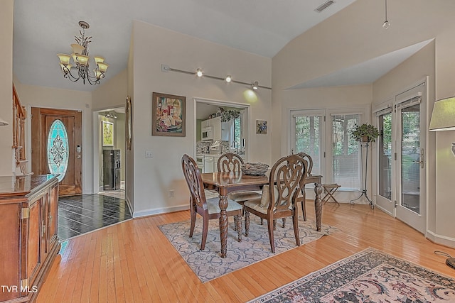 dining space with a notable chandelier, visible vents, lofted ceiling, and hardwood / wood-style floors