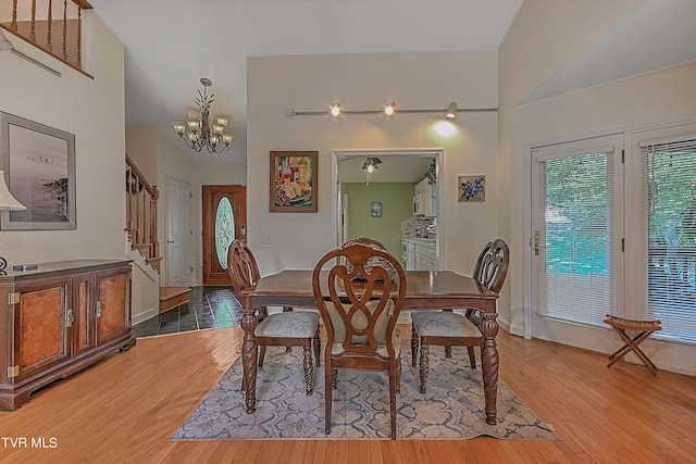 dining room with stairway, baseboards, an inviting chandelier, a high ceiling, and light wood-style floors