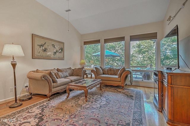 living area with vaulted ceiling, light wood-style floors, baseboards, and visible vents