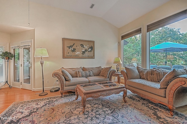 living area featuring light wood finished floors, visible vents, baseboards, and lofted ceiling