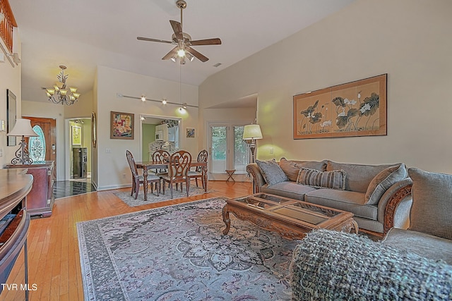 living room with baseboards, high vaulted ceiling, hardwood / wood-style floors, and ceiling fan with notable chandelier